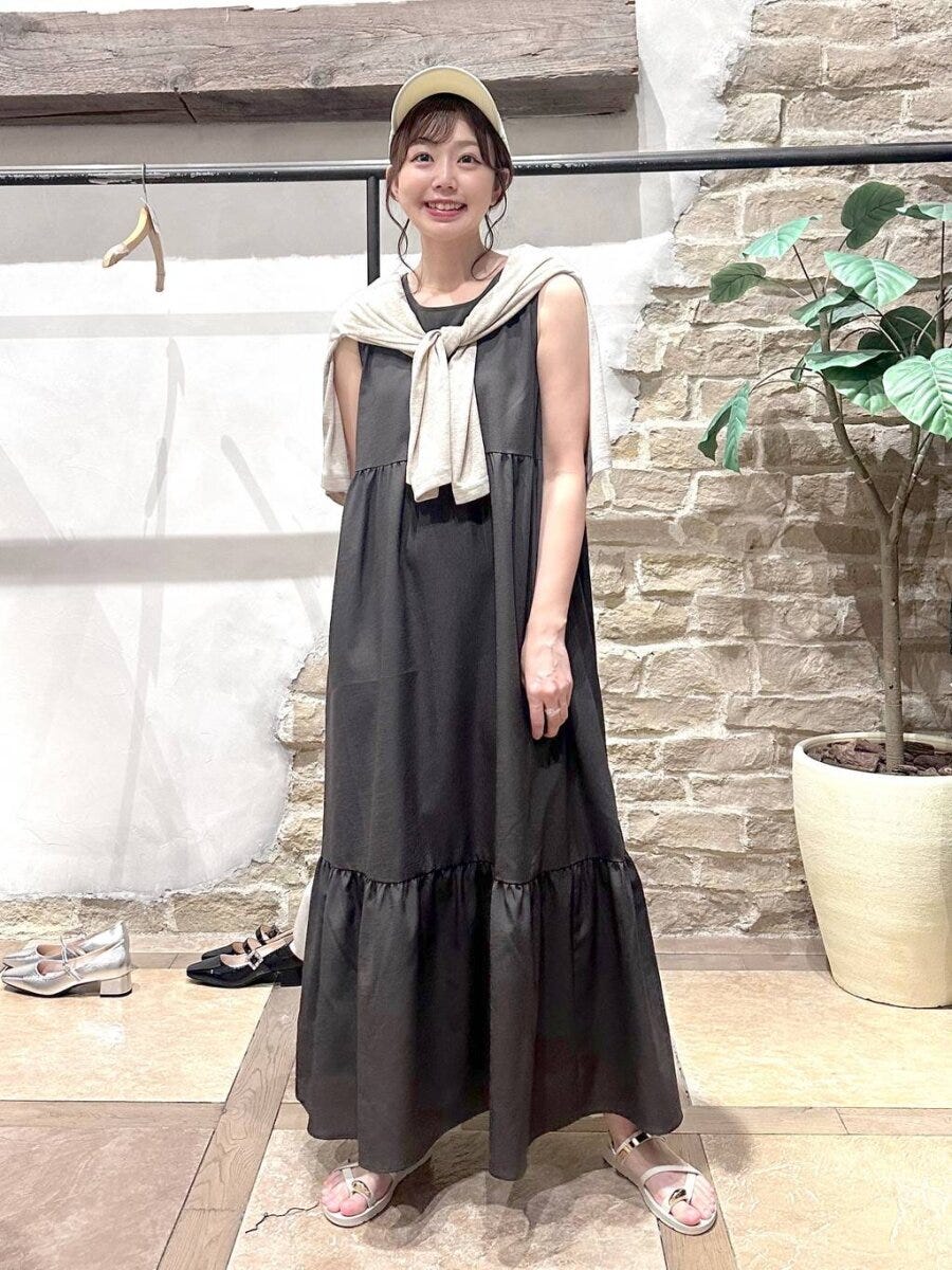 黒ノースリーブワンピにベージュカーデを羽織った女性 黒ノースリーブワンピにベージュカーデを羽織った女性