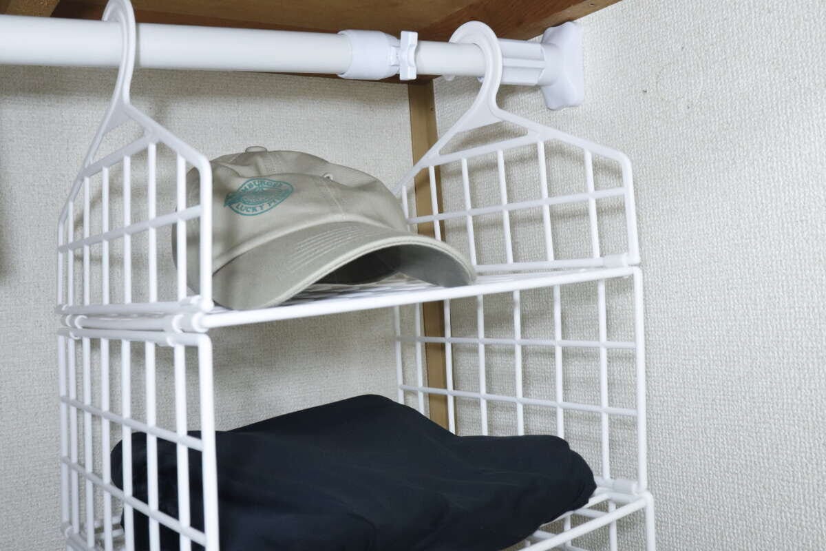 クローゼットに吊るした収納ラックに帽子と服