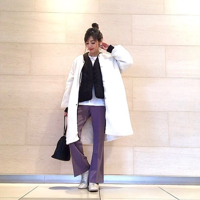 白のカットソーに黒のチャイナカラージャケットと白のノーカラーロングコートを羽織り、パープルのフレアパンツ、白のレースアップブーツ、黒の巾着バッグをコーディネート