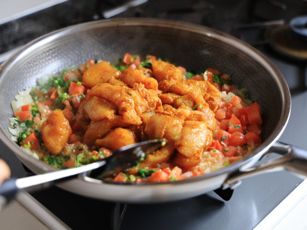 フライパンの野菜にカレー粉をもみ込んだ鶏むね肉を加えた様子