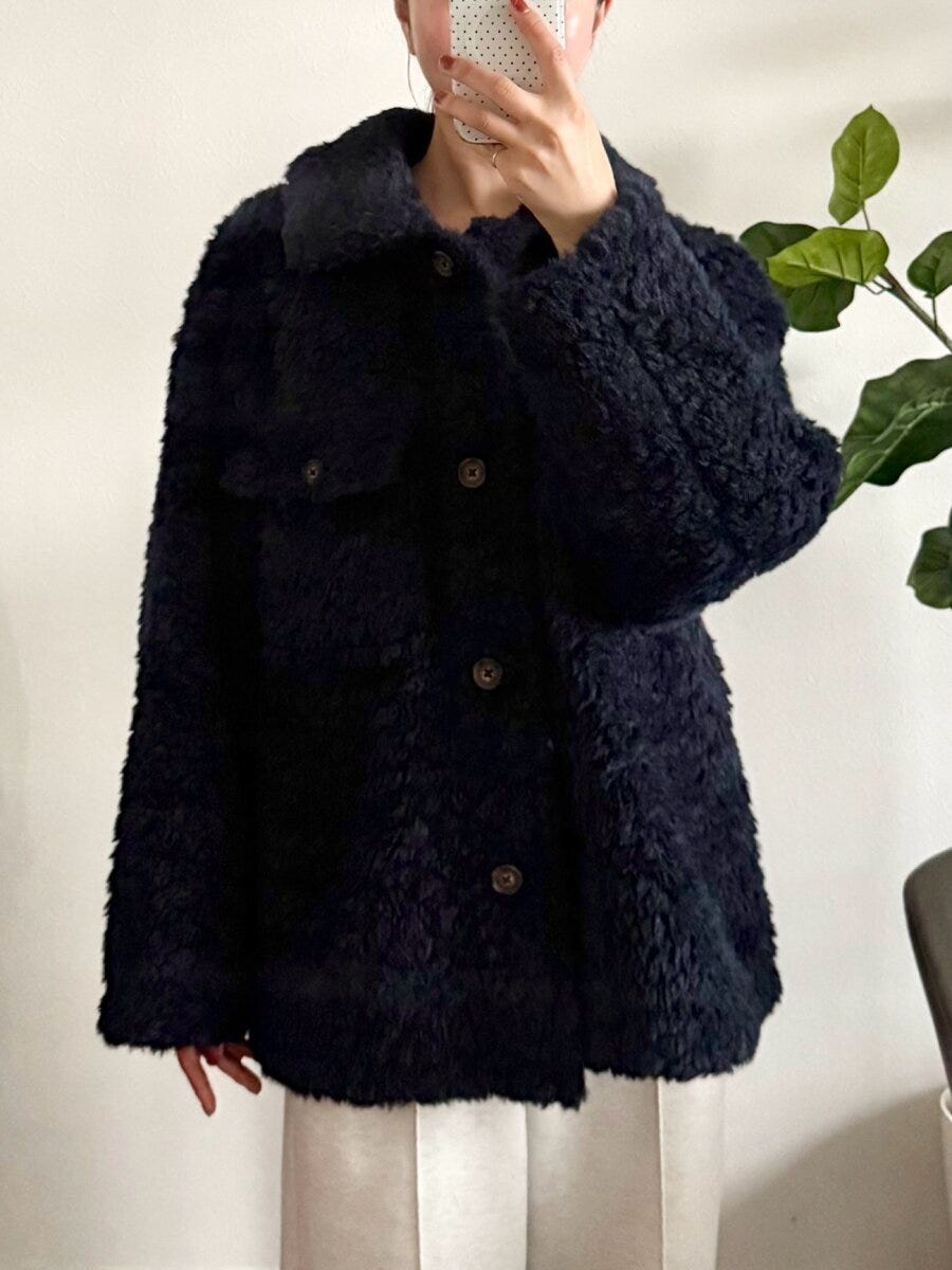 ネイビーのボアジャケットを着用した女性が、スマホで自撮りしている