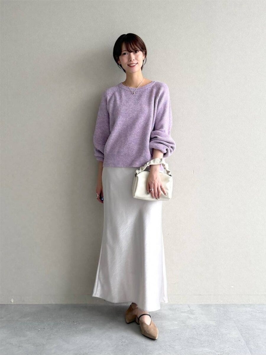 淡いパープルニットと白サテンスカートを着用した女性 淡いパープルニットと白サテンスカートを着用した女性