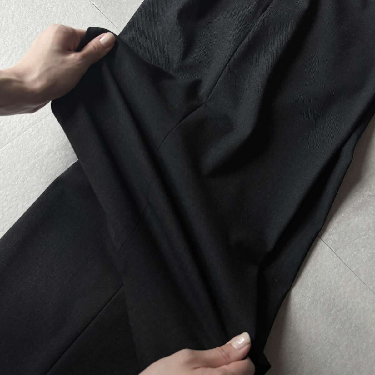 黒いパンツの生地を両手で引っ張り、伸縮性を確認している様子 黒いパンツの生地を両手で引っ張り、伸縮性を確認している様子