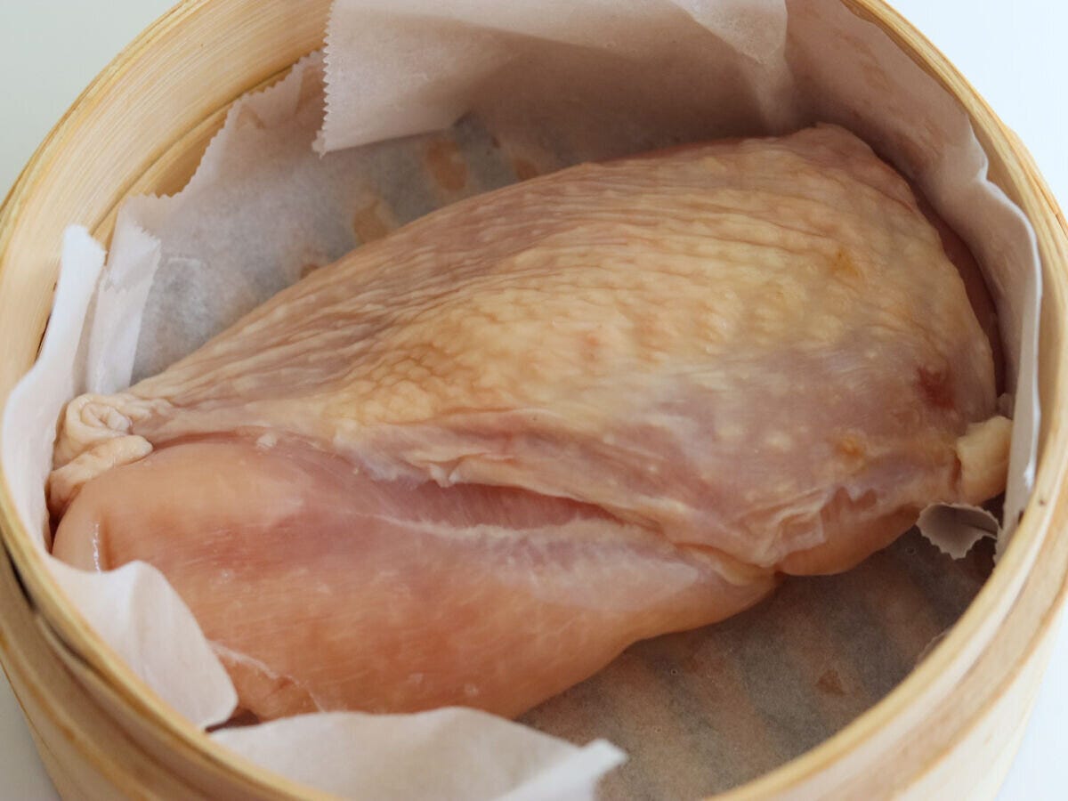 木製のせいろにクッキングシートを敷き皮を上にして鶏むね肉を入れた工程写真