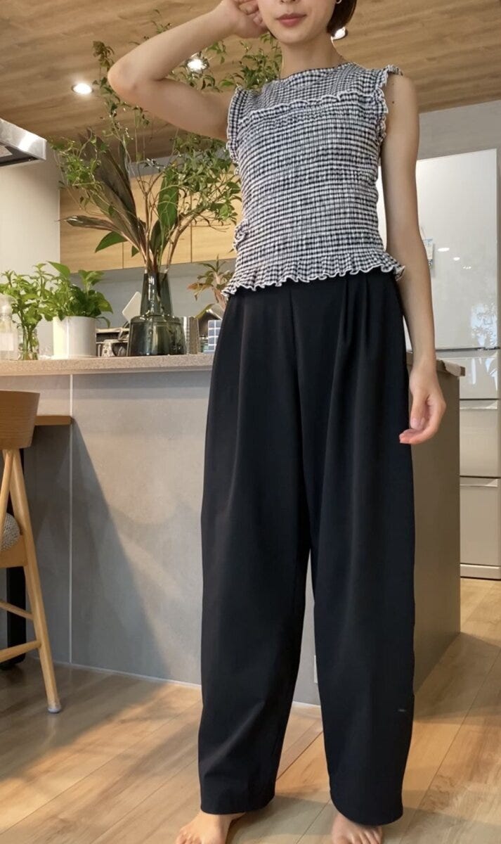黒いワイドパンツとチェック柄トップスを着た女性