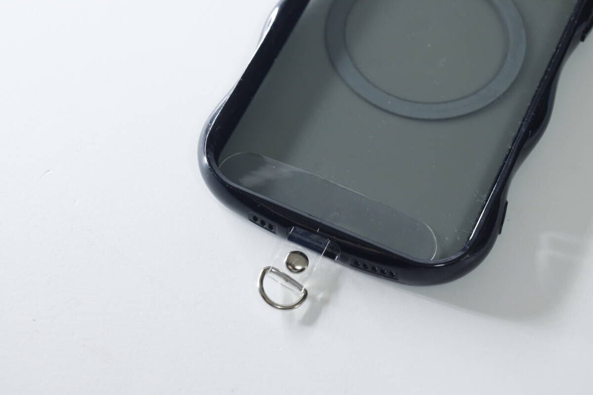 黒いスマホケースの充電口に透明なストラップシートを挟み込んだ状態