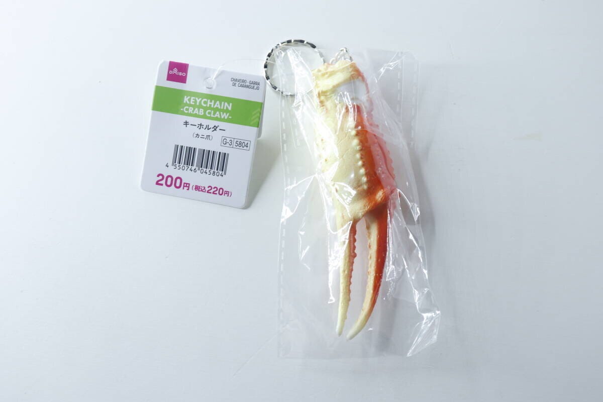 透明な袋に入ったダイソーのカニ爪キーホルダーと商品タグ