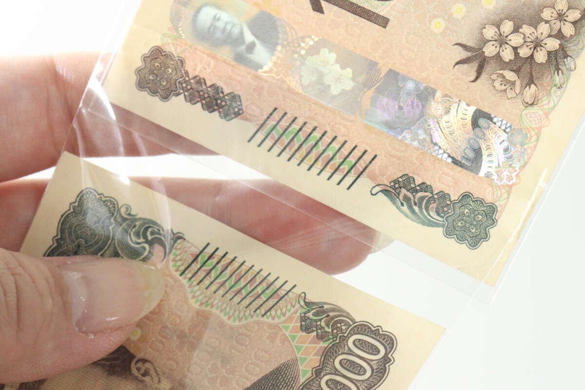 1万円札が入った透明な袋を連結している様子