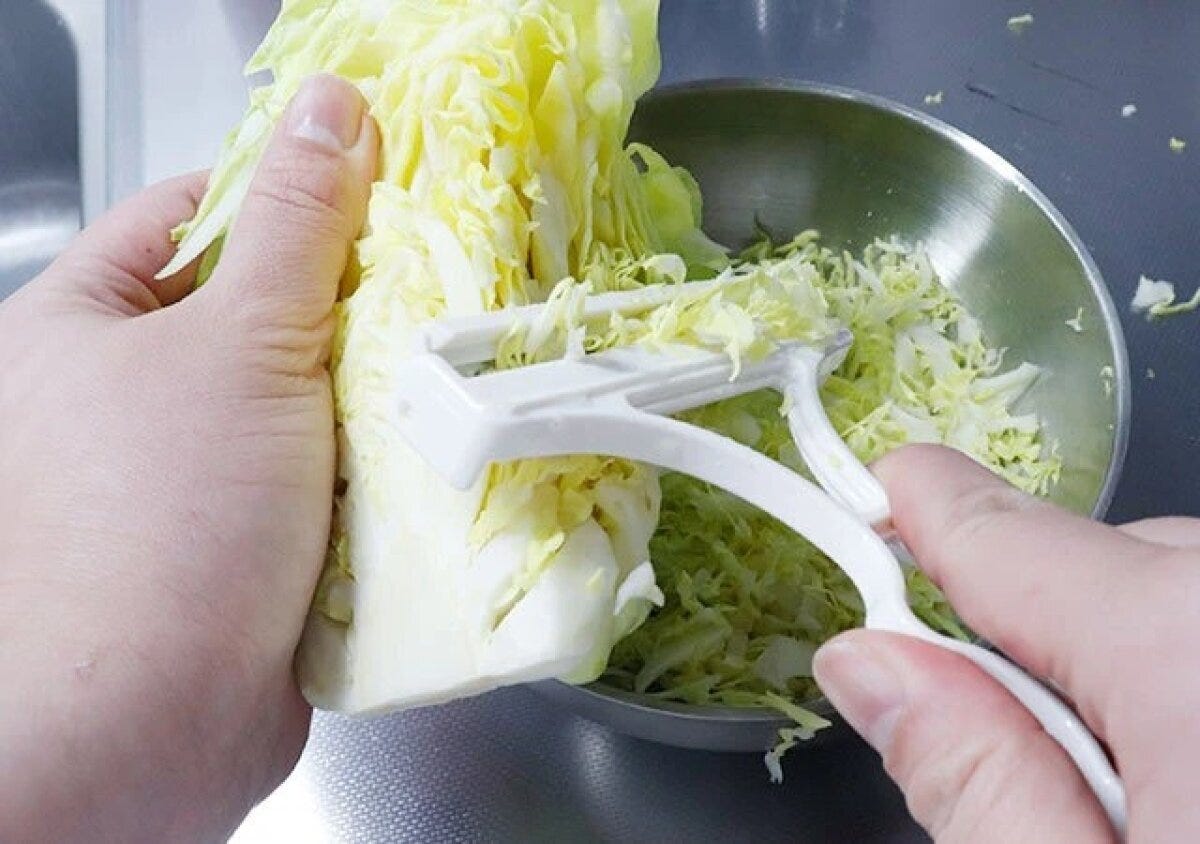 女性がキャベツピーラーでキャベツを細く千切りにしている様子 女性がキャベツピーラーでキャベツを細く千切りにしている様子