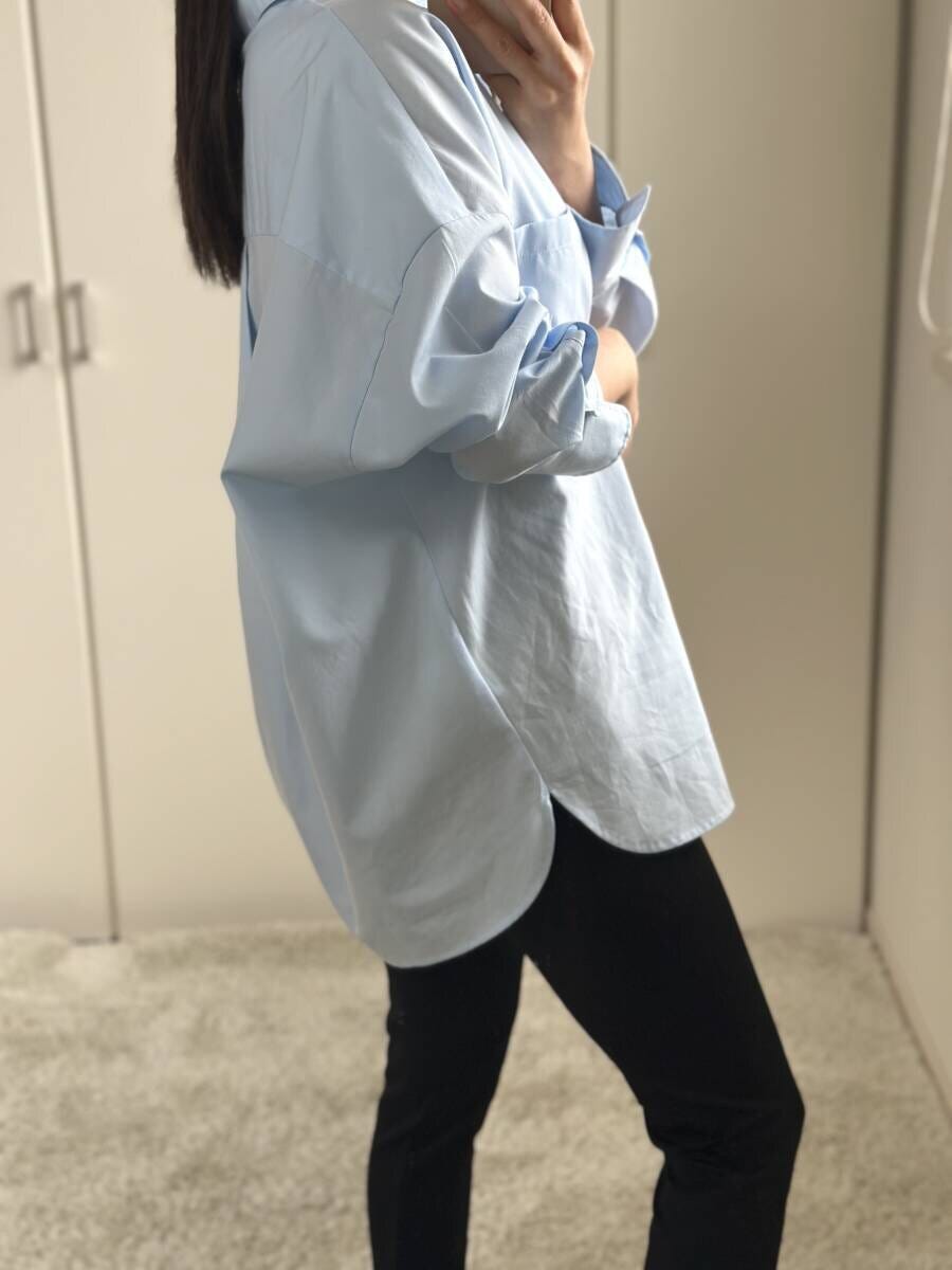 サックスシャツを羽織り黒パンツを履いた女性の横姿 サックスシャツを羽織り黒パンツを履いた女性の横姿