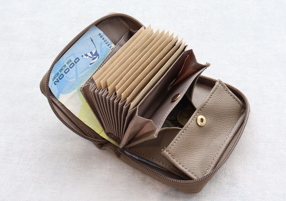 開いた茶色のミニ財布。じゃばら式カードポケットとお札、小銭が見える。 開いた茶色のミニ財布。じゃばら式カードポケットとお札、小銭が見える。