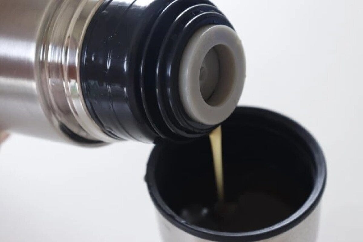 ステンレスボトルからカップにコーヒーのような液体を注いでいる