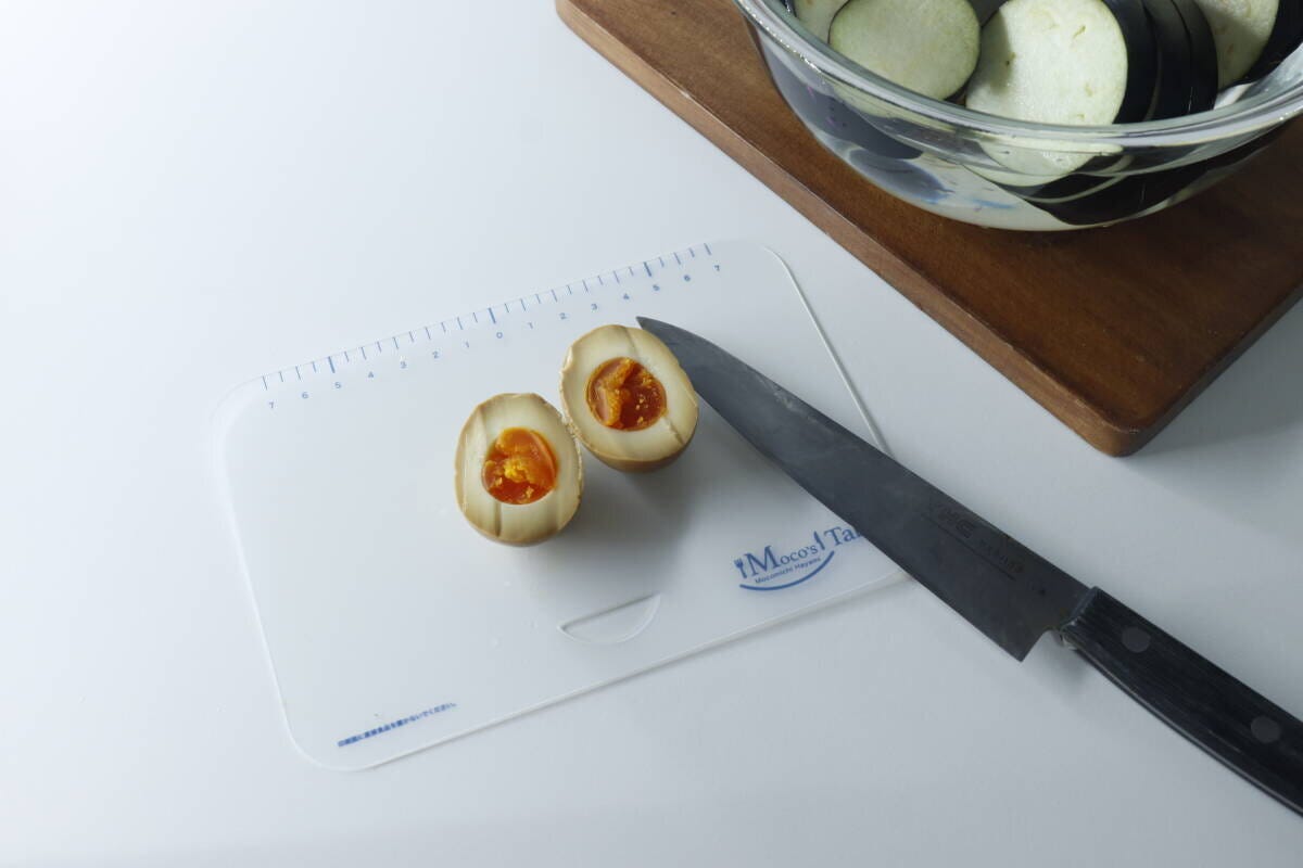 Sサイズのまな板に半分に切った味玉が2つと包丁が置かれている