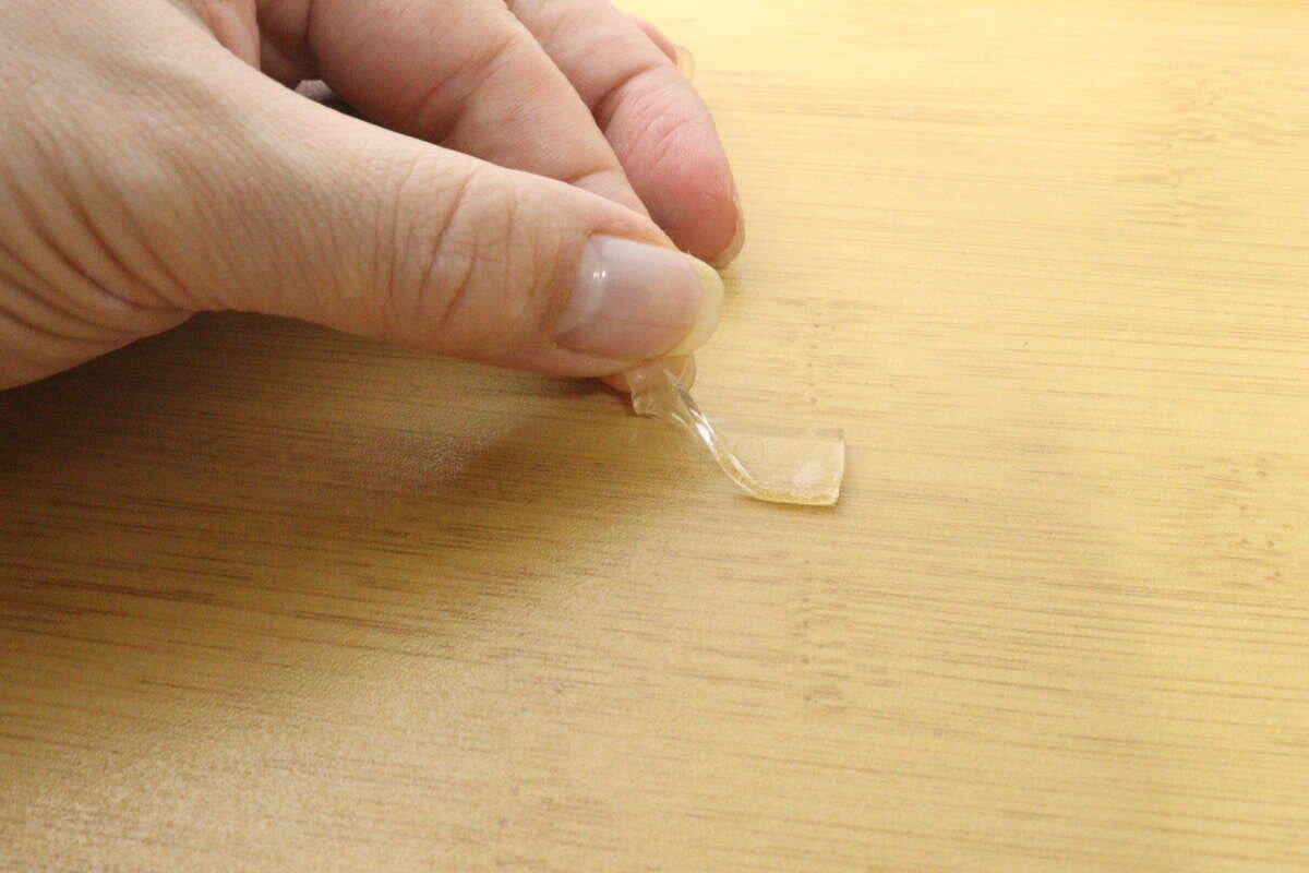 指で木目調トレーからゲルテープを剥がしている様子