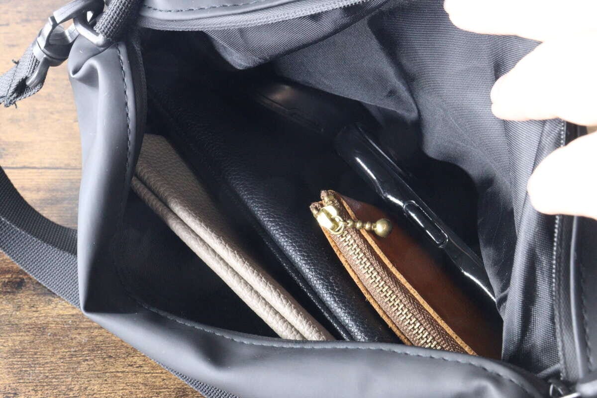 黒いショルダーポーチに長財布やスマホなどが収納されている 黒いショルダーポーチに長財布やスマホなどが収納されている