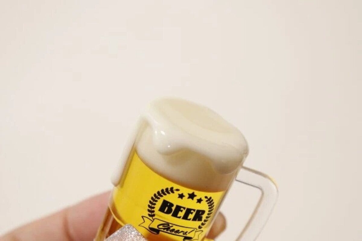 女性がビールジョッキ型キーホルダーを持ち、泡の質感を強調 女性がビールジョッキ型キーホルダーを持ち、泡の質感を強調