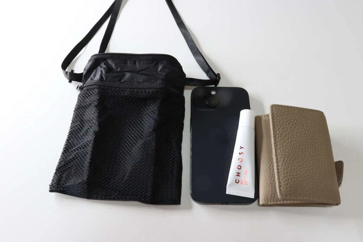黒いトラベルショルダーバッグと、スマホ、リップ、ミニ財布が並べられている