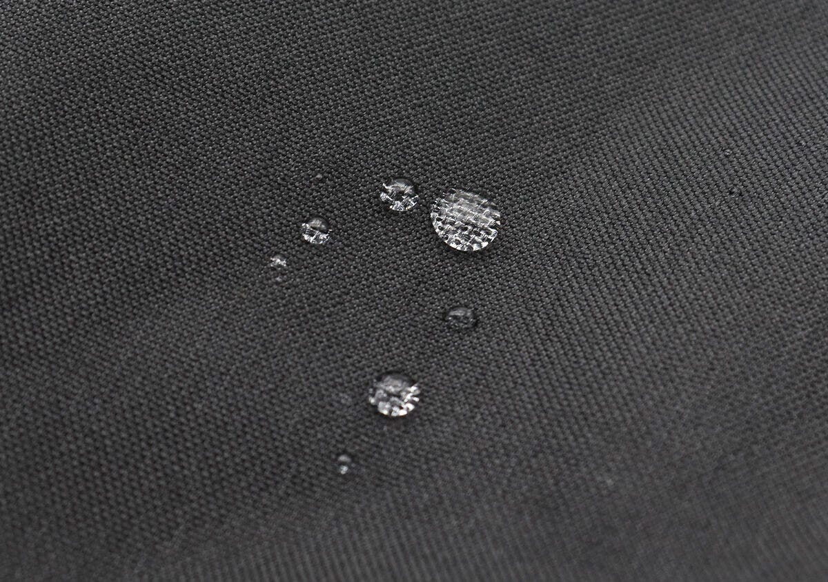黒い生地に水滴が丸く乗っている撥水加工の様子