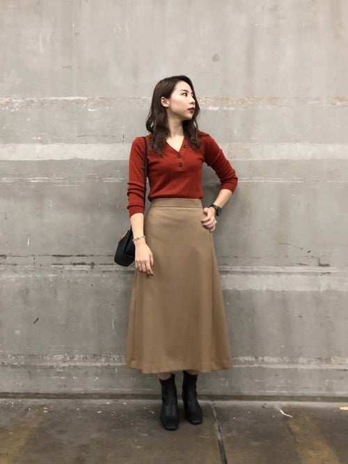 ボタン付きトップスにベージュスカートの女性