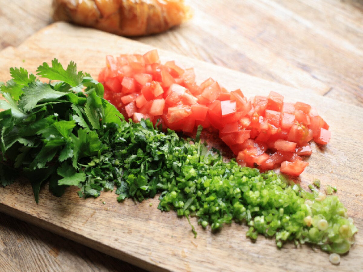 まな板に並んだ角切りのトマトとトッピング用パクチー葉・みじん切りのパクチー