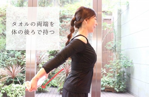 タオルの両端を体の後ろで持つ