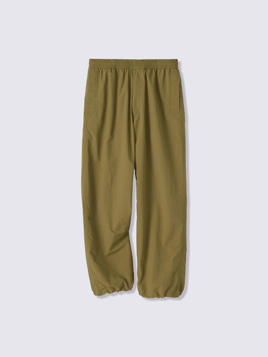 カーキ色のナイロンユーティリティパンツが平置きされている カーキ色のナイロンユーティリティパンツが平置きされている