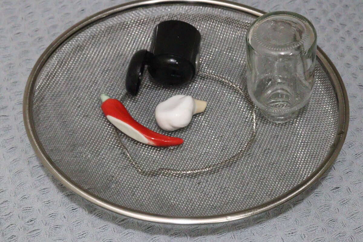 ステンレス製の浅型ザルに小瓶や調味料入れ、唐辛子などが置かれている