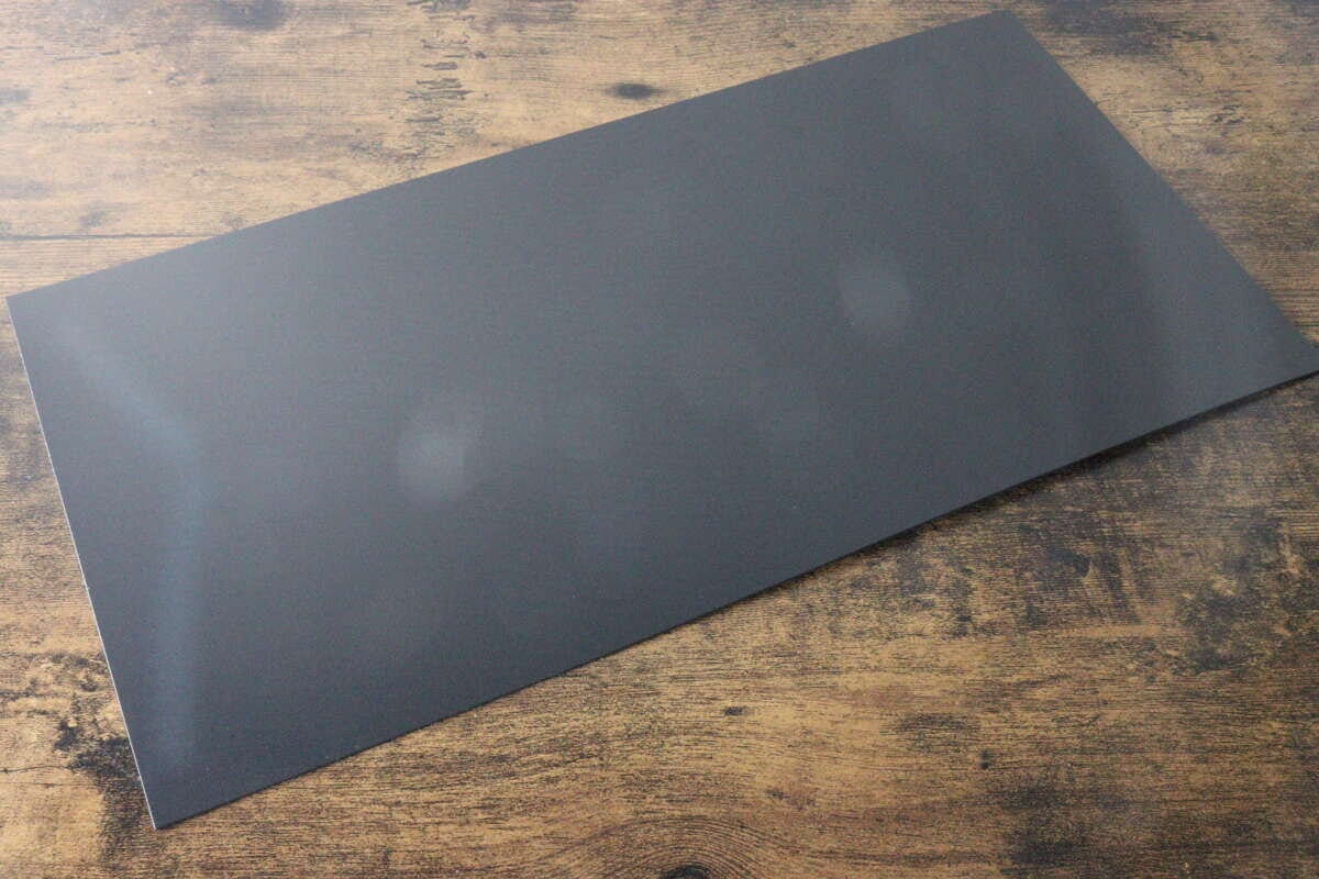 木目調のテーブルに置かれた黒いプラ製の底板 木目調のテーブルに置かれた黒いプラ製の底板