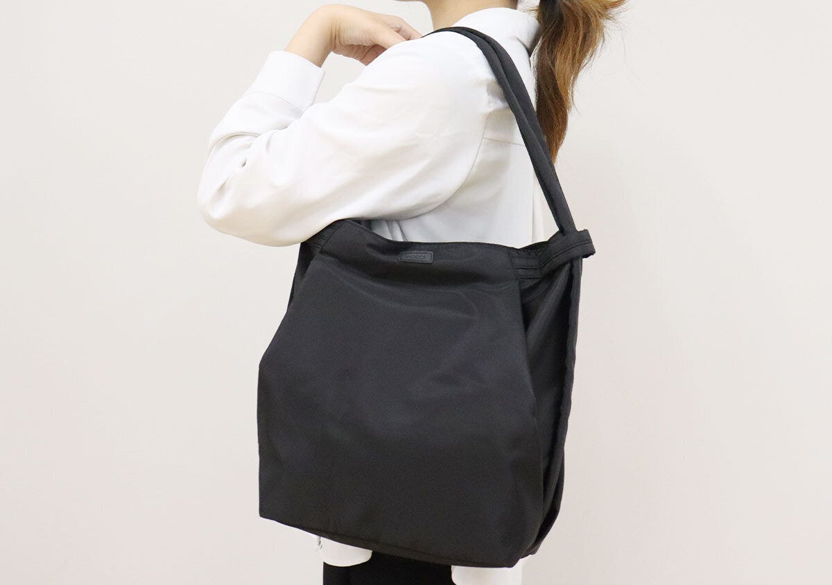 白シャツの女性が黒いバッグをトートとして肩掛け