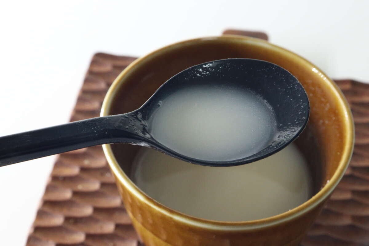 茶色のカップに入ったポタージュスープを、黒いスプーンですくっている様子