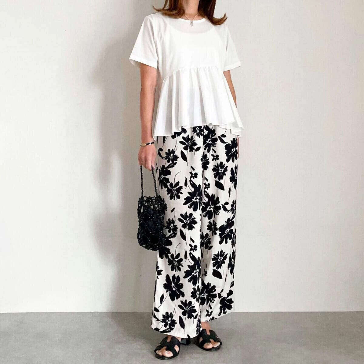 白いTシャツに白黒の花柄ワイドパンツを合わせた女性の全身