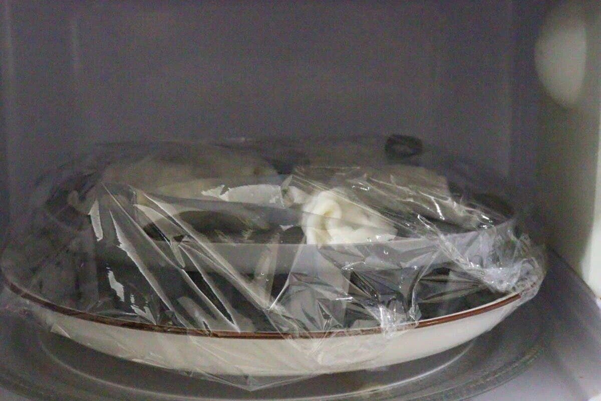 電子レンジの中でラップをかけた皿に蒸し器が入っている様子
