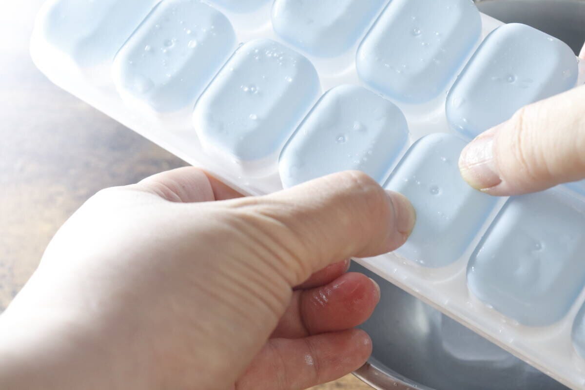 両手でアイストレーの底を押し、氷を一つずつ取り出している様子 両手でアイストレーの底を押し、氷を一つずつ取り出している様子