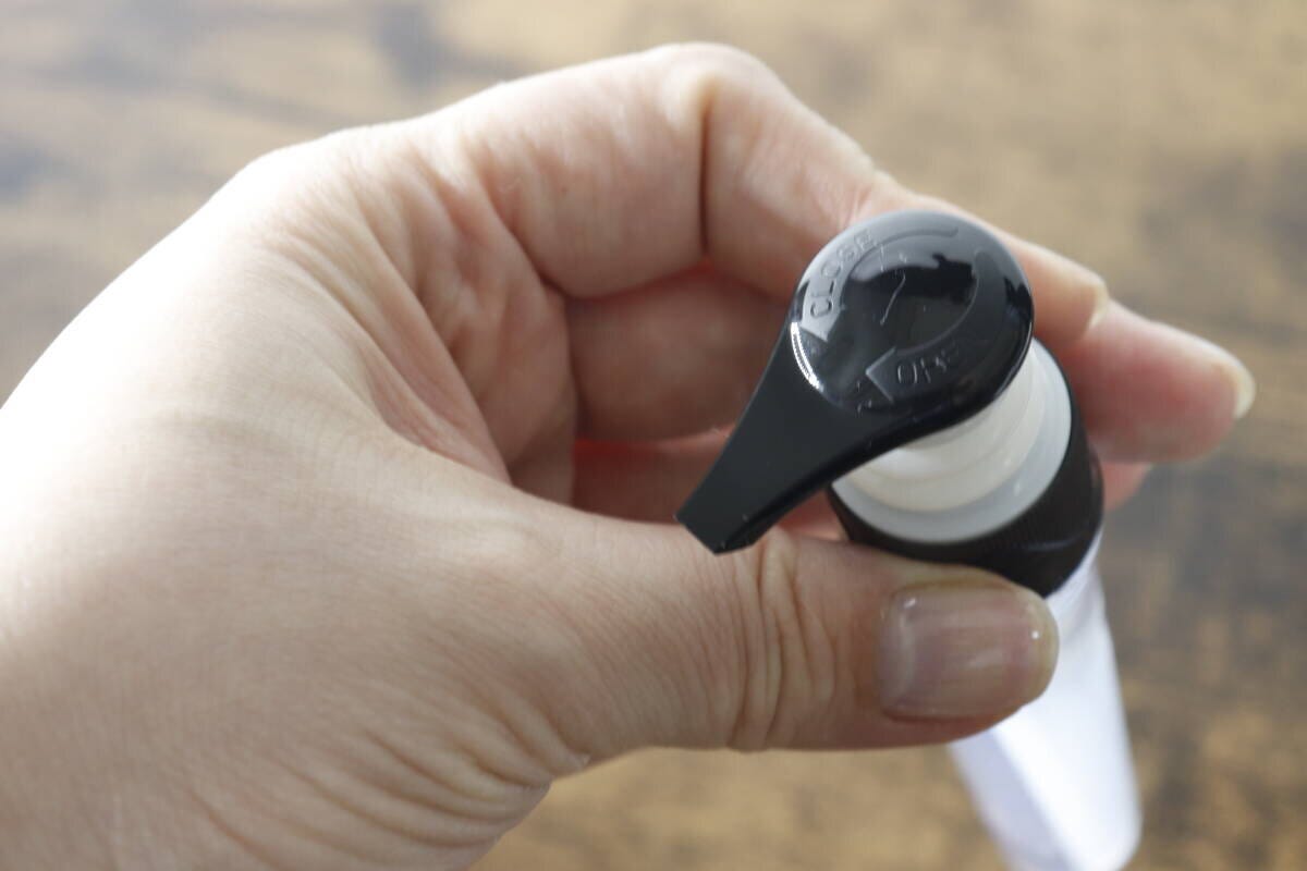 ポンプヘッドのロック機能部分を女性の指で示している ポンプヘッドのロック機能部分を女性の指で示している