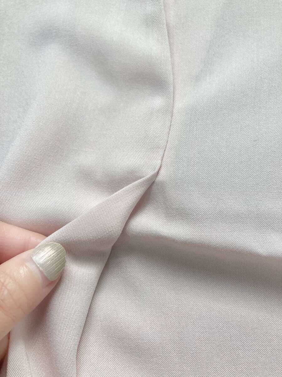 ピンクのブラウスのスキッパー部分を指でつまんで生地感を見せている ピンクのブラウスのスキッパー部分を指でつまんで生地感を見せている