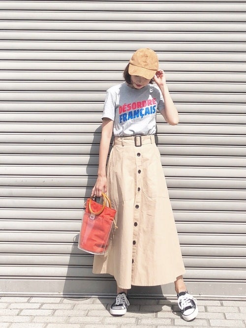グレーのロゴTにベージュのボタンスカートを履いた女性