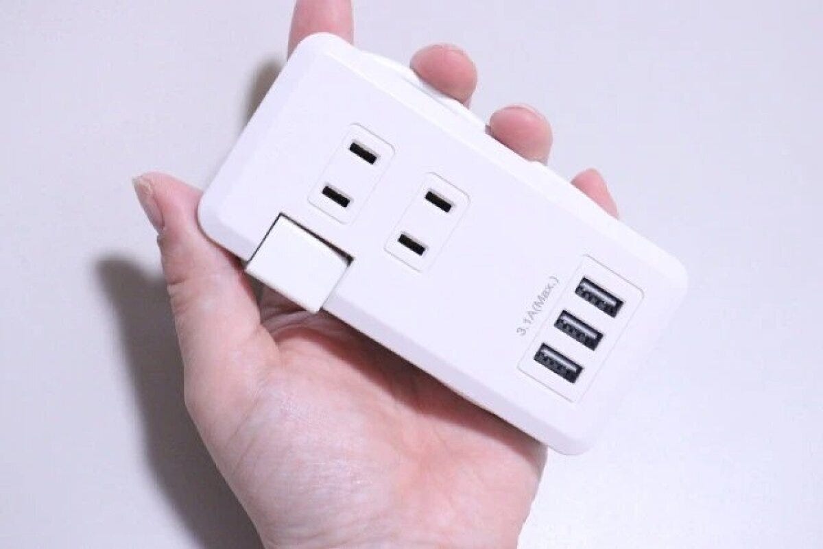 白いコンセントタップを手に持って裏面と側面の構造を示している様子