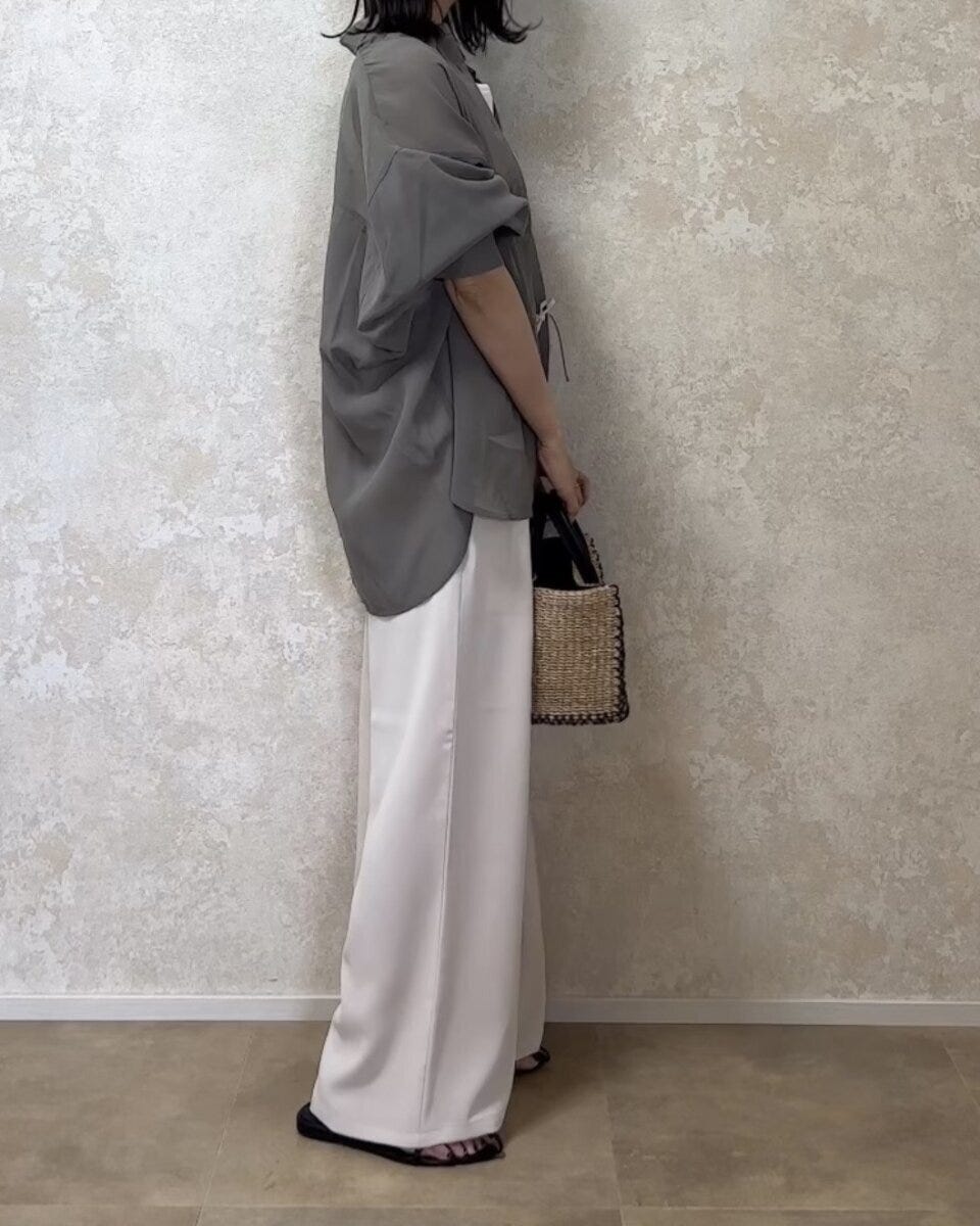 オリーブ色のシアーシャツと淡色ワイドパンツを着用した女性の横姿