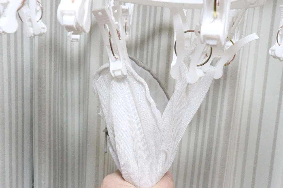 ピンチハンガーから洗濯ネットを引っ張って取り込んでいる手元 ピンチハンガーから洗濯ネットを引っ張って取り込んでいる手元