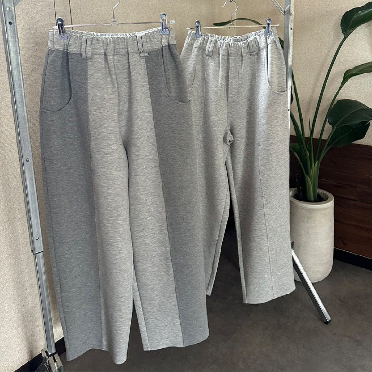 濃淡グレーのカーブシルエットパンツ2本がハンガーに並ぶ