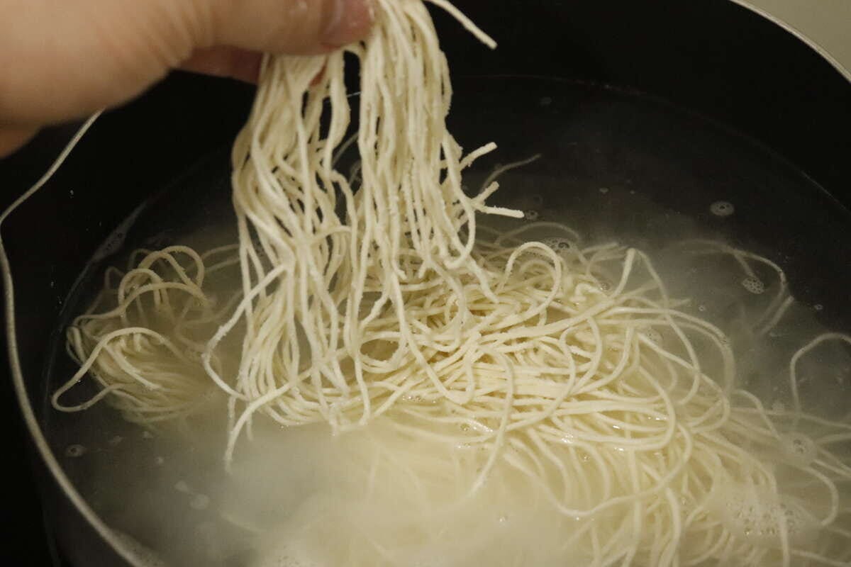 沸騰したお湯の中で白く茹でられている生そうめん 沸騰したお湯の中で白く茹でられている生そうめん