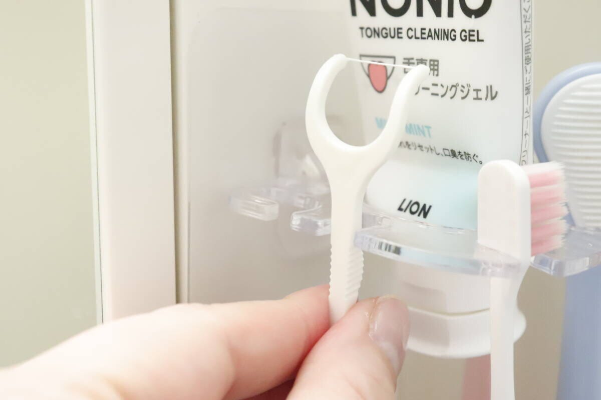 歯ブラシホルダーにY字フロスを引っ掛けている手元 歯ブラシホルダーにY字フロスを引っ掛けている手元