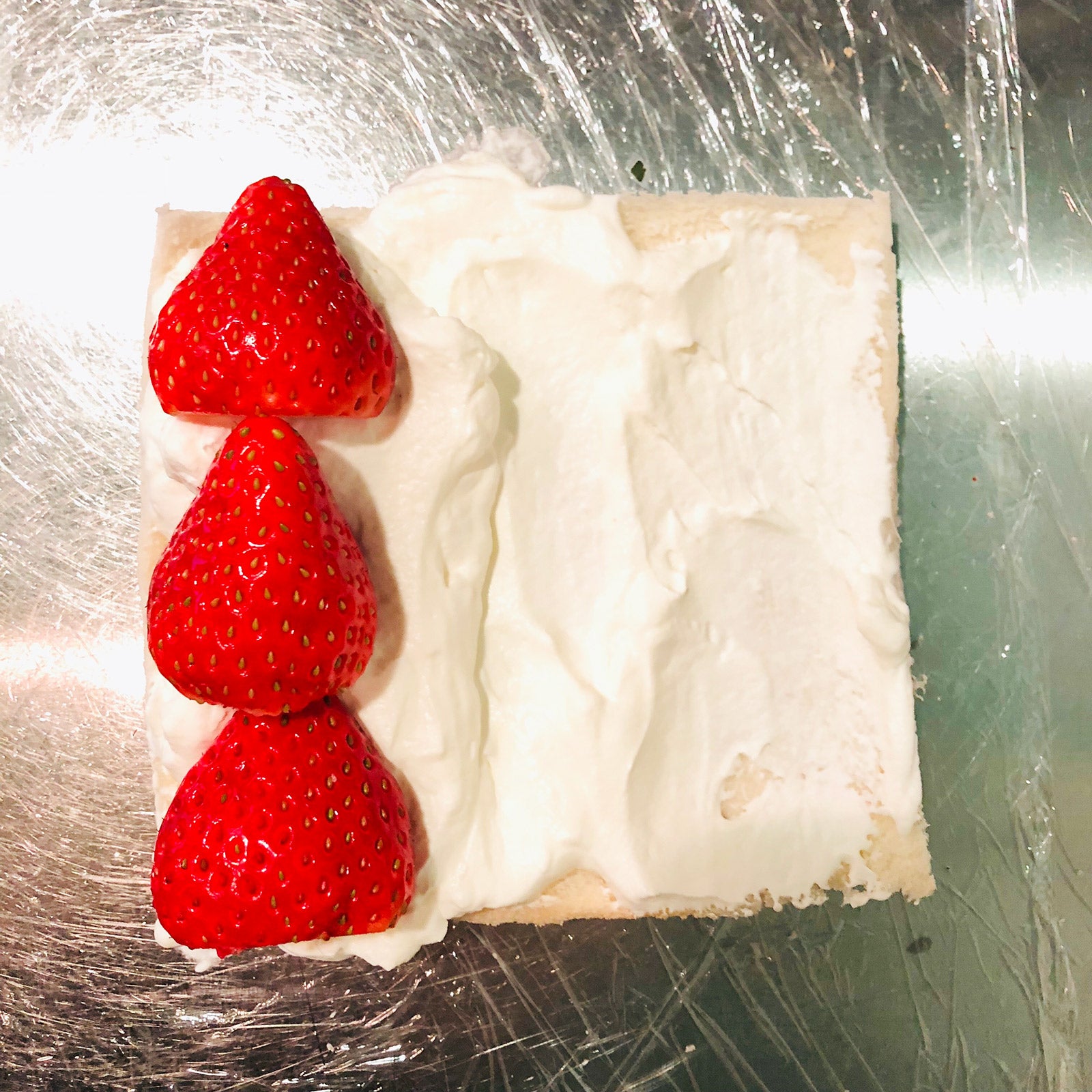 手順2：1枚だけ手前に少し多めに生クリームを塗りいちごを横に並べる／画像提供：柏原歩
