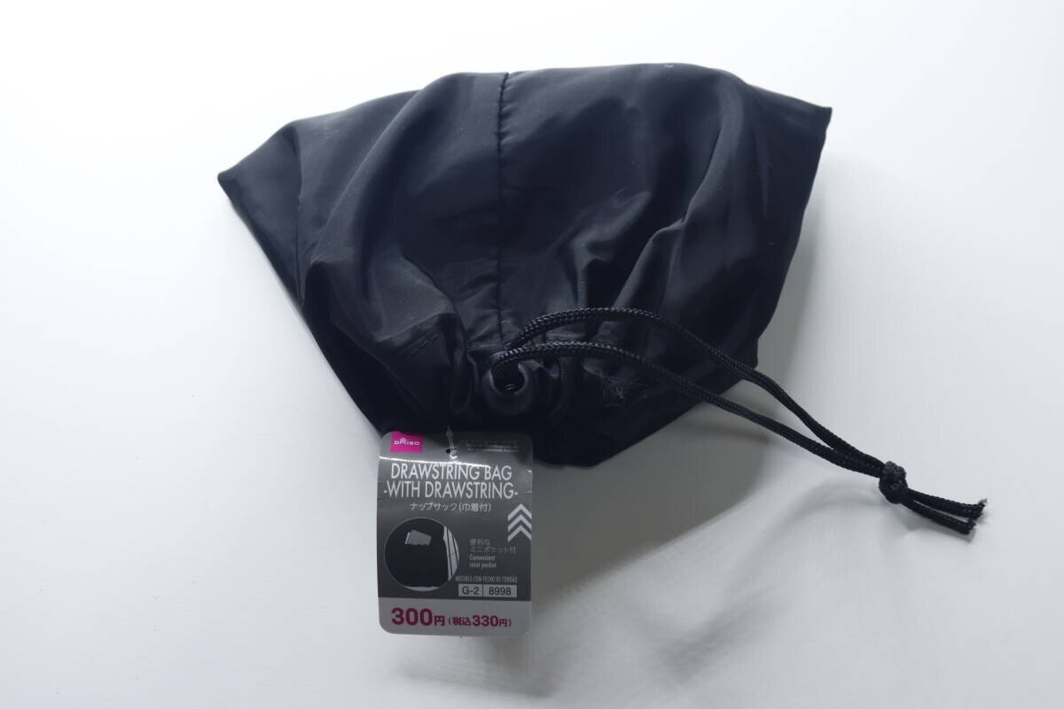 黒い巾着型にたたまれたナップサックと商品タグ