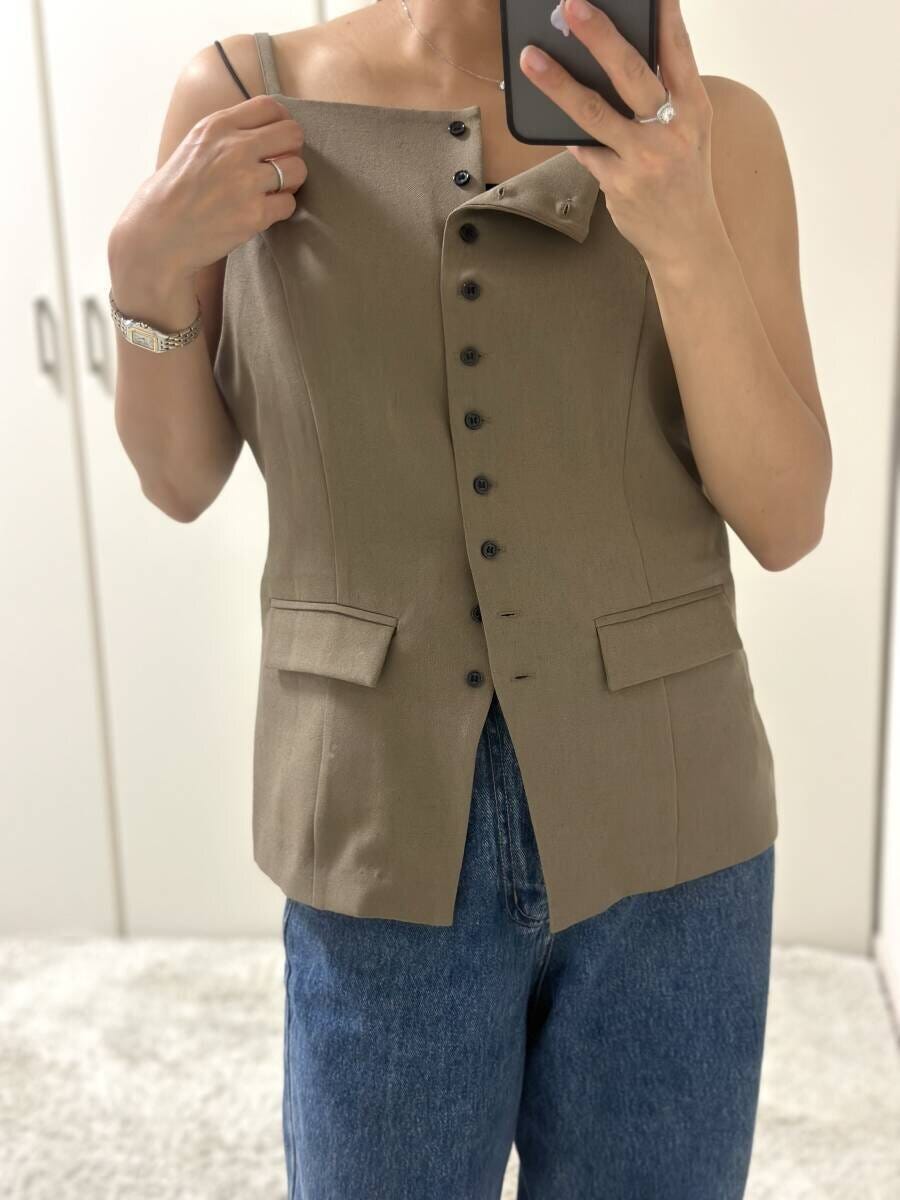 ベージュのツイードキャミトップスを試着する女性 ベージュのツイードキャミトップスを試着する女性
