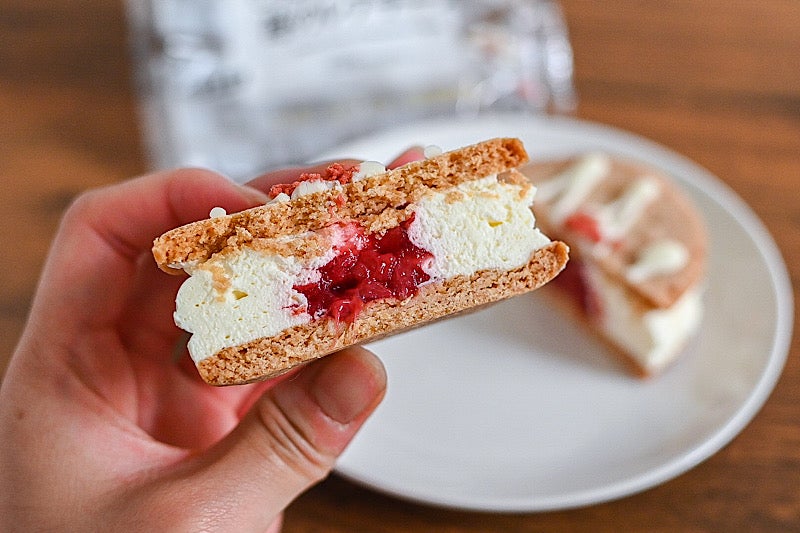 セブンイレブンのしっとりクッキーサンド 苺のレアチーズの半分を持っているところ