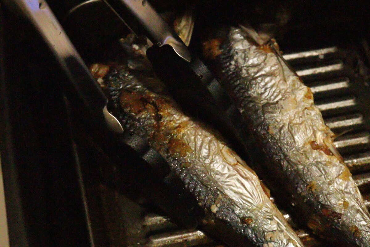 魚焼きグリルで焼かれた魚をダイソーのシリコーントングで優しく掴んでいる様子 魚焼きグリルで焼かれた魚をダイソーのシリコーントングで優しく掴んでいる様子