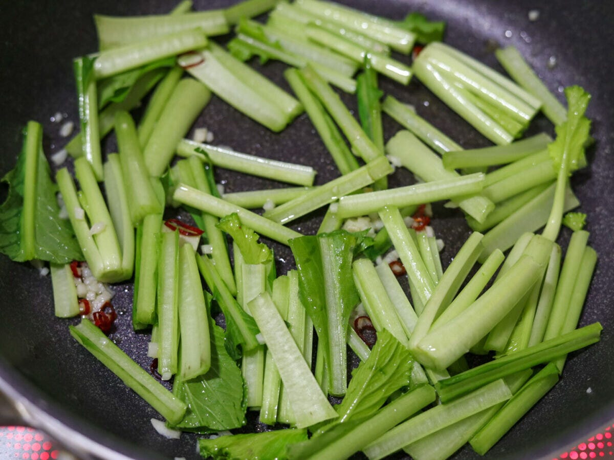 フライパンで小松菜の茎の部分を炒めている様子 フライパンで小松菜の茎の部分を炒めている様子
