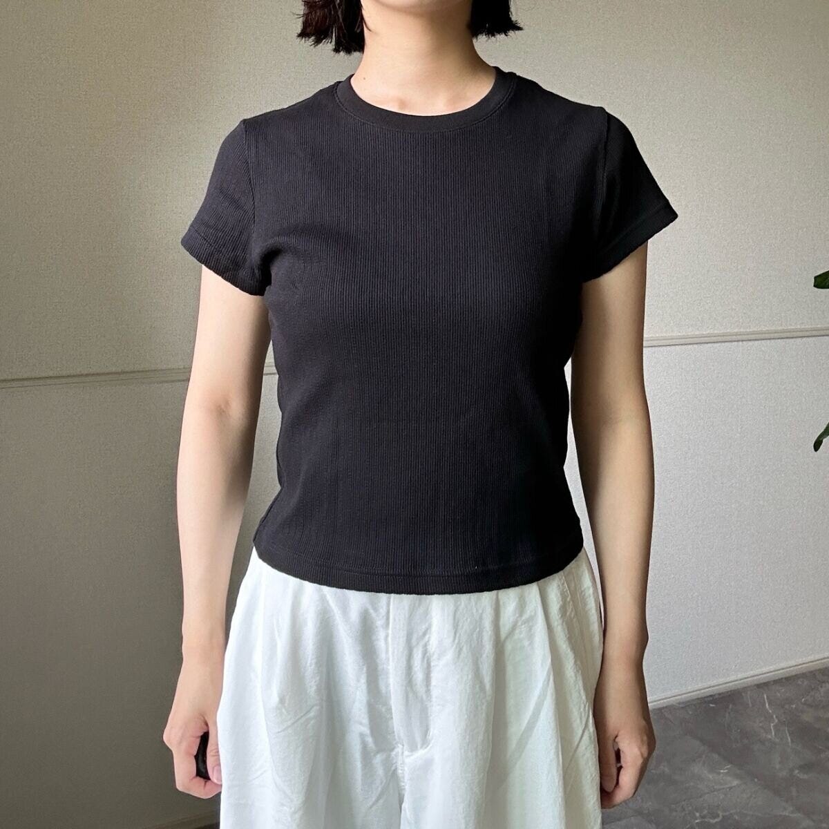 黒いリブミニTシャツと白いワイドパンツを着用した女性の全身 黒いリブミニTシャツと白いワイドパンツを着用した女性の全身