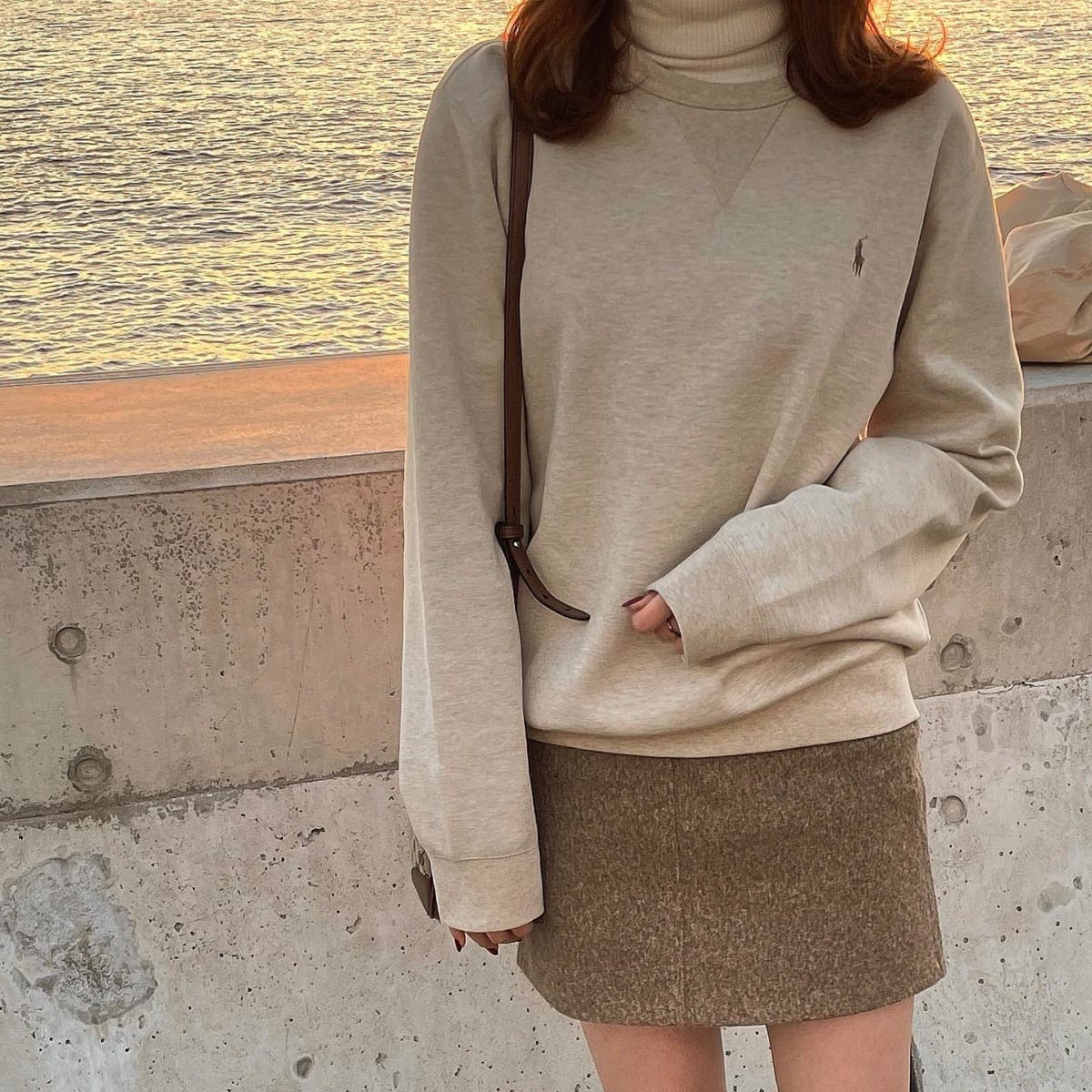 グレーのトレーナーとミニスカートを着た女性